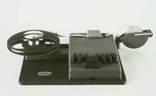 Mechanische Blindenschrift-Stenografiermaschine mit 7 Tasten zum Anschlagen der Punkte, Zwischenraumtaste und Streifenschreiber. Ansicht von vorn : Mechanische Blindenschrift-Stenografiermaschine mit 7 Tasten zum Anschlagen der Punkte, Zwischenraumtaste und Streifenschreiber. Ansicht von vorn. Baujahr: 1950/1955; Hersteller: Firma Karl Neubert . Verwalter: Sächsische Landesbibliothek - Staats- und Universitätsbibliothek Dresden (SLUB), Stenografische Sammlung, Inventar-Nummer R i 0027