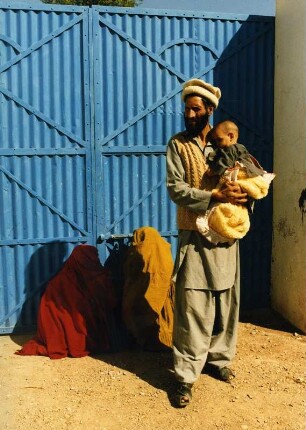 Mann mit Kind, dahinter zwei verschleierte Frauen, Pakistan, in einem afghanischen Flüchtlingslager, ca. 1987