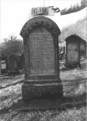 Grabstein 171 (Index: 99608856) Material: Sandstein Zustand: gut Maße HxBxT: 129x60x20 cm Beschreibung: Stele, getreppter, profilierter Sockel, überstehender Rundbogenabschluß, Schriftfeld eingetieft Symbolik: Rundbogenfries Besonderheit: zum Vornamen vgl. 144: Grabstein 171