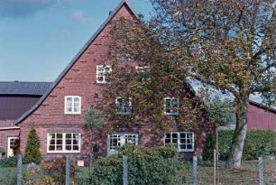 Bünningstedt: Dorfstraße 94: giebelständiges Bauernhaus aus Backstein: Straßenfront Wohntrakt mit Eingangstür, Sprossenfenstern: hinten links Querbau Wirtschaftsgebäude [angeschnitten]: Vorgarten, Baum, Maschendrahtzaun