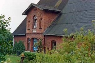 Seefeld 1a: giebelständiges Bauernhaus aus Backstein: Traufseite, Teilansicht: Wohntrakt mit Eingangsrisalit, daran oben Jahreszahl 1898: Garten