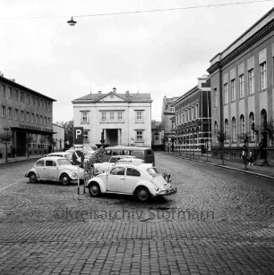 Markt: vorne parkende Pkws, rechts das Stadthaus, links die Kreissparkasse Stormarn, mittig im Hintergrund das Rathaus: Blick von Süden