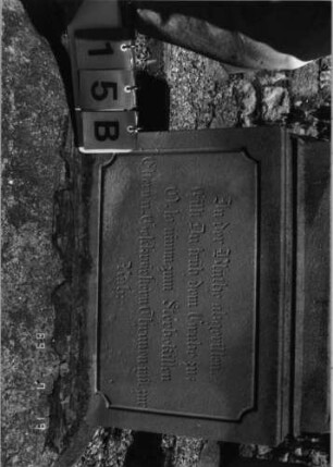 Grabstein 15 (Index: 99796571) Material: Sandstein Zustand: quer gebrochen/repariert Maße HxBxT: 177x63x22 cm Beschreibung: Rundbogenabschl. m. kl. Verdach. u. Mittelakroter, Schrift eingetieft m. Sonderformabsc Symbolik: Blüte, Zackenfries: Grabstein 15B