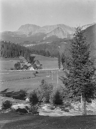 Am Bach : Ein Tal mit Bach und Gehöft. Im Hintergrund Gebirge