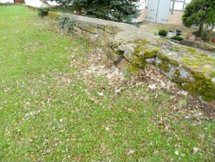 Heina-Evangelische Kirche - Kirchhof im Süden - Kirchhofmauer mit Steinansatz nach Norden (ehemaliger Turmansatz oder Quermauer der einst wehrhaften Kirchhofmauer)