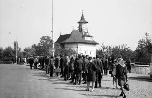 Suceava: Menschenansammlung an Bushaltestelle, Hintergrund Kirche