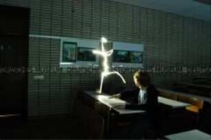 Sitzender Schüler in einem Klassenraum mit weißer Lichtfigur auf dem Tisch (Prämiertes Foto Sonderthema: Wunderland) (Altersgruppe S)