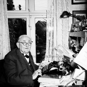 Clasen, Martin: geboren 1882, gestorben 9. November 1962: von 1909 bis 1924 evangelischer Pastor in Neustadt, von 1924 bis 1947 Pastor in Reinfeld; Heimatforscher, Begründer des Heimatmuseums Reinfeld, ehrenamtlicher Archivpfleger: Einwohner von Reinfeld: Aufnahme aus Anlass seines 50-jährigen Amtsjubiläums als Geistlicher, an seinem Arbeitsplatz vor Schreibmaschine: Träger des Bundesverdienstkreuzes am Bande