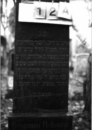 Grabstein 12 (Index: 99751701) Material: Granit Zustand: gut Maße HxBxT: 176x49x21 cm Beschreibung: Stele, getreppter Sockel, giebelartiger Abschluß Symbolik: segnende Hände, Blüten, eckige Voluten: Grabstein 12A