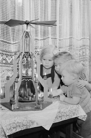 Drei Kinder vor einer Weihnachtspyramide