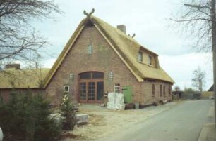 Vinzier: Schäferkamp 2: traufständige Kate mit Reetdach: Straßenfront mit breiter Gaube: Giebelseite Wirtschaftstrakt mit ehemaligem Scheunentor: links rechtwinkliger Stallanbau: Dach neu gedeckt, als Giebelzier Pferdeköpfe