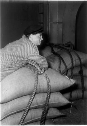 Hamburg. Freihafen. Im Laderaum des Frachtschiffes sind die gestapelten Säcke zum Löschen vorbereitet. Ein Schauermann legt eine Pause ein. Er wartet sicherlich darauf, dass er den Stapel an den Kran hängen kann.