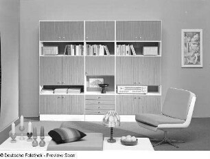Drehstuhl : Wohnzimmermöbel. Anbauwand (1973; Möbelkombinat Nord (MKN)). Ansicht mit Drehstuhl, Hocker und Beistelltischen
