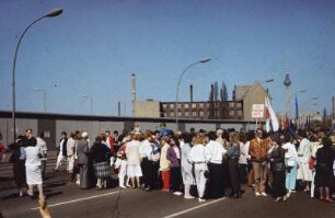 DDR. Berlin. Teilnehmer der Demonstration zum Ersten Mai entlang der Berliner Mauer. Ansicht mit Transparent "PGH Friseure Mitte"
