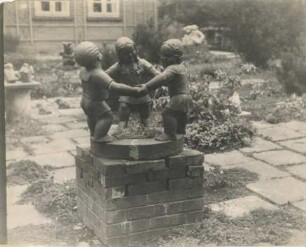 Drei Kinder bei Ringelreihen: Gartenskulptur: Rohlfshagen, Kupfermühle: Schäferkate, im Garten, auf Backsteinsockel: hinten weitere Skulpturen