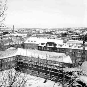 Erweiterungsbau mit Kreistagssitzungssaal [später Gebäude C]: IV. Bauabschnitt: Gebäude mit gedecktem Dach und Gerüst: vorn rechts Kreistagssitzungssaal: Blick vom Erweiterungsbau "Hochhaus" [später Gebäude B]: dahinter Wohnblocks an der Reimer-Hansen-Straße und der Mewesstraße: Winter