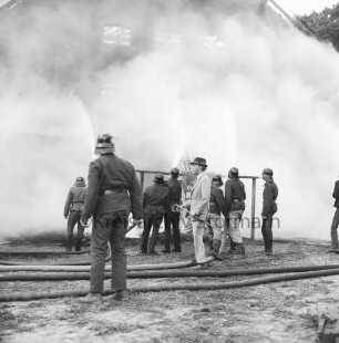 Gut Altfresenburg: Brand des Bullenstalls: Brandruine: Giebelfront mit Lastenaufzug: davor Feuerwehrleute, Mann in Anzug mit Spazierstock und Wasserschläuche: hinten Rauchschwaden: 24. August 1971
