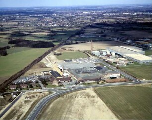 British American Tobacco (BAT): Luftbild des Gewerbegebietes am Beimoorweg: im Vordergrund Beimoorweg, links Bahnstrecke Hamburg-Lübeck, im Hintergrund Delingsdorf und Bargteheide