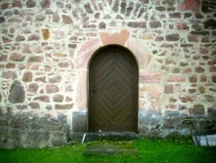 Evangelische Kirche - Kirchturm (romanische Gründung) von Westen - Erdgeschoß mit Eingang und rundbogigem Gewände sowie Werksteinen im Mauersteinverband