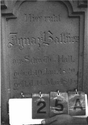 Grabstein 25 (Index: 100106724) Material: Sandstein Zustand: verwittert, Lettern in Gold nachgezogen Maße HxBxT: 155x49x16 cm Beschreibung: Stele, eingezogener Rundbogenabschluß mit Verdachung, Mittelpalmette, getreppter Sockel, Schriftfeld eingetieft in Sonderform Symbolik: floral: Grabstein 25A
