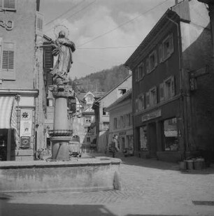 Tiengen (Hochrhein). Marienbrunnen in der Tiengener Hauptstraße, mit Blick in die Zubergasse. Am Ende dieser Gasse befindet sich das älteste Haus der Stadt mit einem Sgraffitto, welches die Eroberung und Zerstörung Tiengens durch die Eidgenossen im Jahr 1499 zeigt. Brunnen, Haus und Sgraffitto sind bis heute erhalten