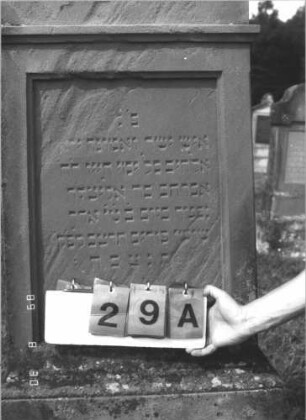Grabstein 29 (Index: 99609665) Material: Sandstein Zustand: teilweise stark verwittert Maße HxBxT: 183x69x30 cm Beschreibung: Stele, Giebelabschluß mit Verdachung, Mittelpalmette, Schriftfeld eingetieft, getreppter Sockel, unten Rusticaimitat: Grabstein 29A