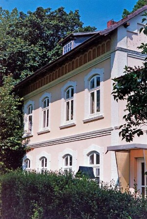Bahnhofstraße 53: ehemaliges Bahnhofsgebäude der Südstormarnschen Kreisbahn: Traufseite an früherem Bahnverlauf, rechts Anbau mit Eingangstür: Hecke, hinten Bäume