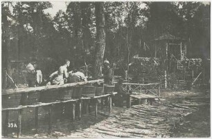Waldlager vor Verdun, sieben Soldaten an Waschvorrichtung (hölzerne Zuber auf Knüppelgang), im Hintergrund Pavillon
