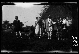 Einheimische in Tracht vor einem reetgedeckten Holzhaus