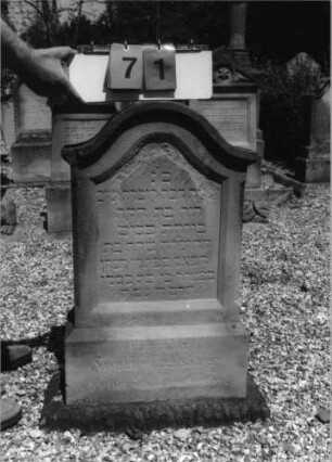 Grabstein 71 (Index: 99796682) Material: Sandstein Zustand: abgeblätt/verwitt/Textverl Maße HxBxT: 83x49x20 cm Beschreibung: Stele, Sockel, Konvexbogenabschluß, Schrift eingetieft: Grabstein 71