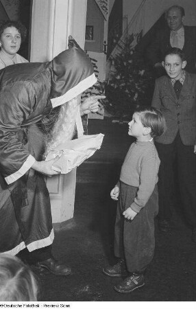 Weihnachtsmann beim Überreichen von Geschenken an Kinder auf der Weihnachtsfeier des VEB Kartographie