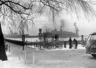 Hamburg-Flottbek. Fähranleger in Teufelsbrück, dem Mündungsbereich des Baches Flottbek in die Elbe, im Winter. Im Hintergrund die Werftanlagen der Deutschen Werft in Finkenwerder