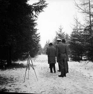 Polizei: Mord an der Hamburger Küchenhilfe Edeltraut Harloff am 26. November 1965: Oher Tannen: Leichenfundort zwischen Tannen und Totholz: in der Mitte Gruppe von Polizeibeamten der Lübecker und der Hamburger Mordkommission auf Weg: links Fotostativ: hinten Tannen: Winter