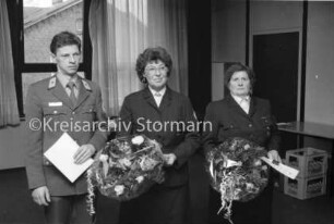 DRK-Ortsverein Reinfeld: Begegnungsstätte: Jahresversammlung: Ehrung der aktiven Mitglieder Ernst Hansen, Elfriede Rahmstorf, Telse Plautz mit Urkunden und Blumensträußen: hinten Fensterfront, Tür und Tisch