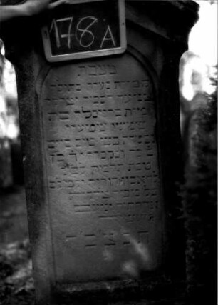 Grabstein 178 (Index: 100109711) Material: Sandstein Zustand: verwittert Maße HxBxT: 170x63x24 cm Beschreibung: Stele, getreppter Sockel, giebelartiger Abschluß mit Verdachung, Schriftfeld eingetieft mit Rundbogenabschluß: Grabstein 178A