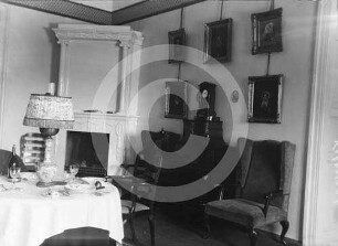 Esstisch, Kamin und Porträtgalerie eines Zimmers im Herrenhaus von Gut Alt-Kalnemoise