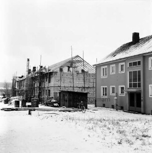Wohnungsbau: Lütjenseer Straße: zwei Wohnblocks: hinterer Block im Rohbau: rechts davor Baubude und Baumaterial: Winter