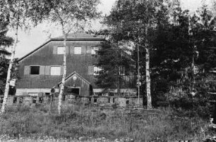 Männer vor einem Holzhaus im Wald, vermutlich während eines Ausfluges