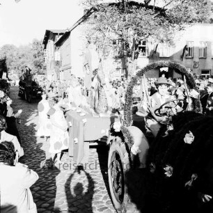 Karpfenfest: Umzug: Ahrensböker Straße: Festwagen, Neptun mit Nymphen und Seepferdchen, gezogen von geschmücktem Traktor, Begleiterinnen: dahinter weiterer Festwagen: links und hinten Zuschauer, Bildmitte Hotel Stadt Hamburg, Baum, rechts Einmündung von Paul-von-Schoenaich-Straße: im Vordergrund Schatten des Fotografen, 11. Oktober 1959
