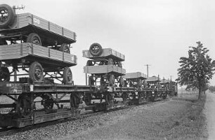 Güterzug einer Schmalspurbahn mit Rollwagen, darauf Flachwagen mit z. T. doppelt übereinandergestellten LKW-Anhängern, Juli 1956 - Februar 1957