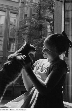 Porträt eines Mädchens mit einer Katze an einem offenem Fenster