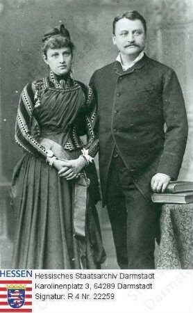Hochgesand, Hermann (1859-1913) / Porträt mit Ehefrau Katharina geb. Müller (1850-1916) in Raum neben Tisch mit Büchern stehend, Kniestücke