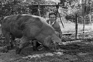 Hof von Günther Fielmann: Besitzer hockend bei der Fütterung von Schwein Borsti