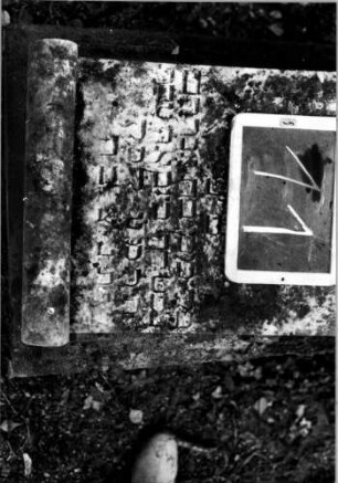 Grabstein 11 (Index: 100110408) Material: Sandstein, Schriftplatte Marmor Zustand: stark verwittert mit Textverlust, Schriftplatte beschädigt Maße HxBxT: 82x56x44 cm Beschreibung: Steinsarg mit Schriftplatte Symbolik: Schriftplatte in Pergamentrollenform: Grabstein 11 (Detailaufnahme 1)