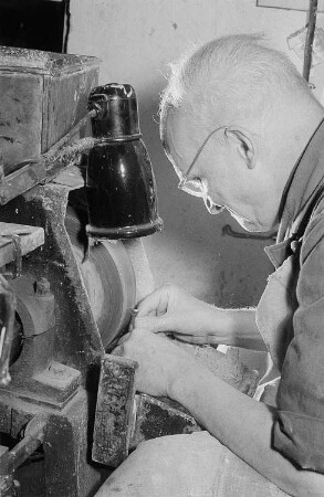 Herr Pomsel, Mitarbeiter der Werkstatt der Edelsteinschleifermeister Antes und Zerfas in der Harkortstraße, schleift einen Rohling in Form