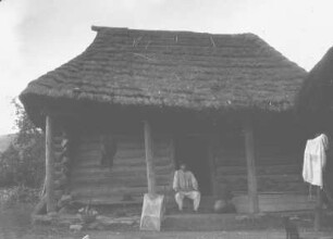 Haus in Ayutla : Mann sitzt vor einem Holzhaus