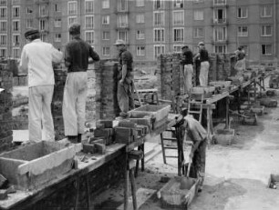 Dresden. Maurer und freiwillige Aufbauhelfer bauen Garagen zwischen Großblock-Wohnbauten oder eine Kaufhalle