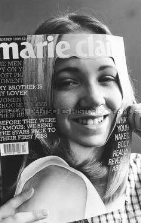 Junge Frau hält sich ein "Marie Clair" Titelblatt mit ausgeschnittenem Gesicht vor ihr Gesicht (Altersgruppe 14-17)