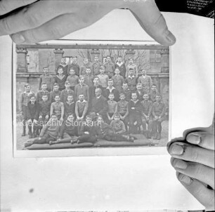 Reproduktion eines Fotos: Gruppenbild einer Schulklasse mit Lehrer