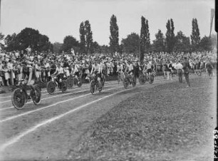 Dresden, Festzug von Sportlern auf der Aschenbahn eines Sportplatzes mit Zuschauern, angeführt von Fahrradfahrern, vermutlich Schüler